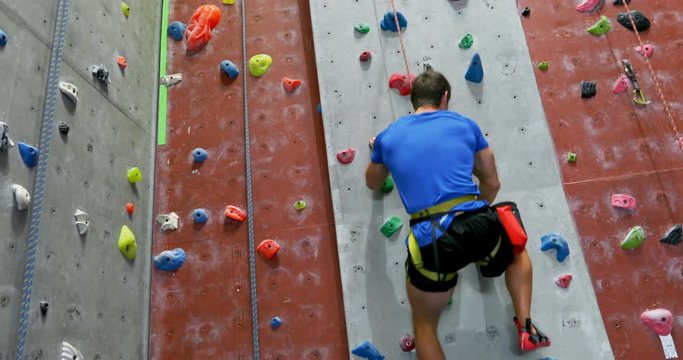 Man practicing rock climbing in fitness studio 