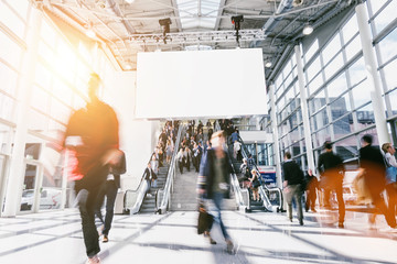 large crowd of anonymous blurred people at a trade show, including banner for text