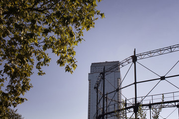 View of glass skyscraper through a tree and old amusement park's ride in Istanbul.