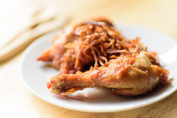Fried chicken leg with fried onion on top ready for eating
