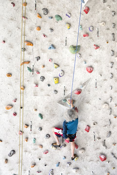 Senior man rock climbing indoors on an artificial wall