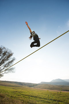 Man jumping on slackline outdoor on a green meadow