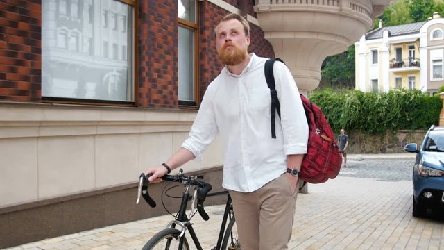 4k video of stylish bearded man walking with retro fixed gear bicycle on street