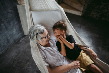 Happy grandma reading with grandson in hammock