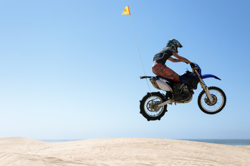 Teenager jumping sand dunes on a motorcycle