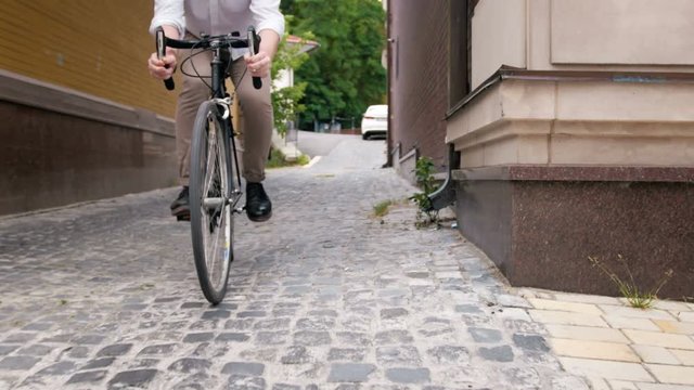 4k steadicam video of young man riding bicycle on old narrow street