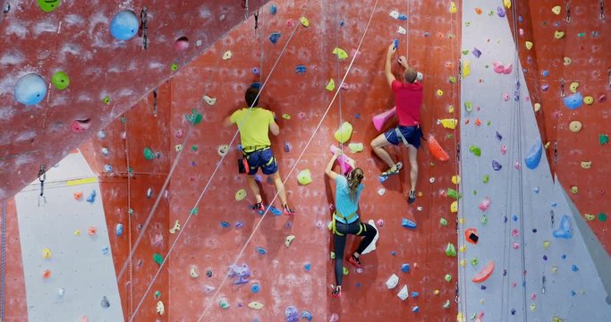 Men and woman practicing rock climbing in fitness studio 