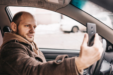 Young handsome man taking selfie inside his new car