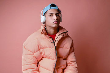 Portrait of a young man listening to music wearing a pink coat