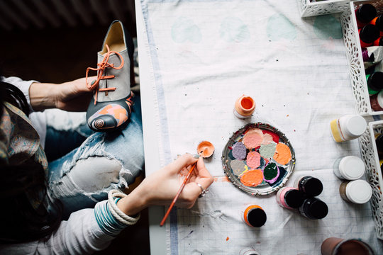Female designer decorating shoes