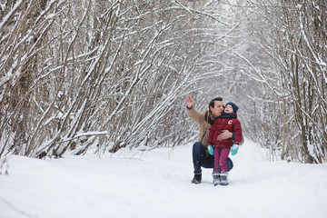Fototapeta na wymiar Young family with children are walking in the winter park. Winte