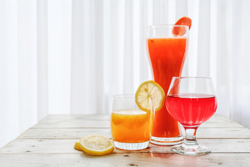 Orange juice and cocktail in white glass put on vintage wood table in kitchen.