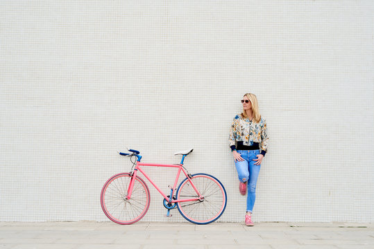 Stylish woman with fixie over white wall.