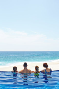Family with two kids on edge of infinity pool overlooking ocean