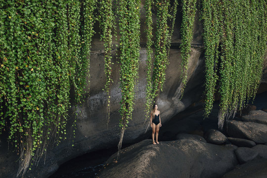 Woman standing on rock beside ocean