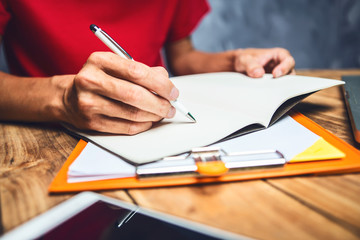 Man hand writting, Business man working hard seriously work at home concept, he is wearing red shirt.