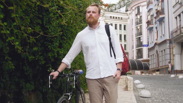4k video of handsome bearded man travelling with bicycle at old european city