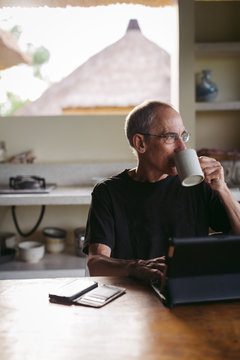 Mature man in his 60's working and traveling with tablet in trop