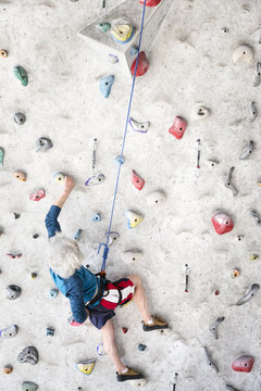 Senior man rock climbing indoors on an artificial wall