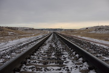 Low angle view of empty train tracks through a cold snowy winter landscape in rural Wyoming