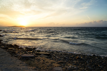 Beautiful sunset scenic copyspace wavy seaview and natural rock beach with shades of orange and blue sky background