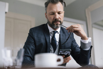 Businessman in hotel room using his smartphone
