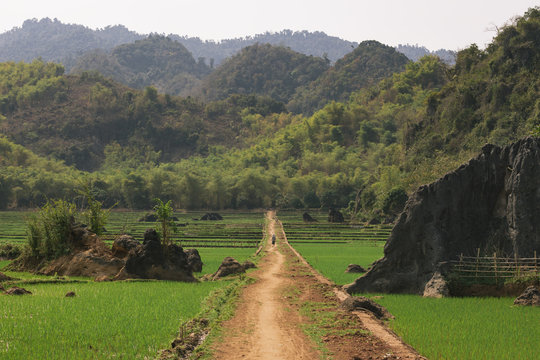 Dusty road in the hills of Vietnam, surrounded by paddies and hills.