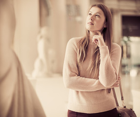 Fototapeta premium Girl looking at ancient sculptures in art museum