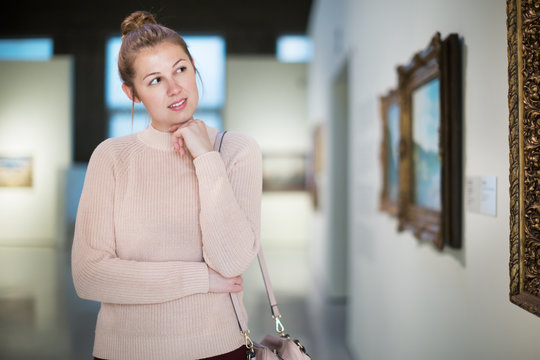 Woman standing near painting in art museum