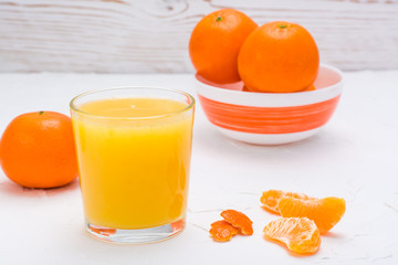 Mandarin juice in a glass and ripe mandarins on a table