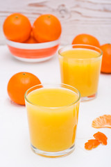 Mandarin juice in a glass and slices of tangerines on a table
