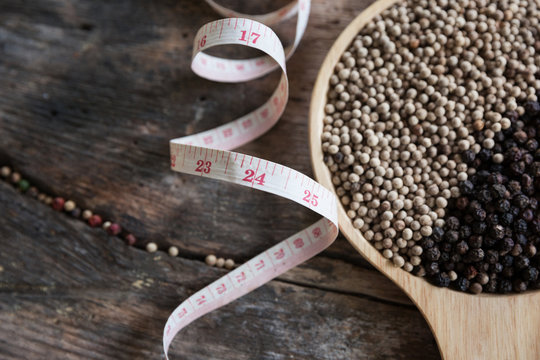 Black pepper with measuring tape on wooden table ,diet concept nutrition.