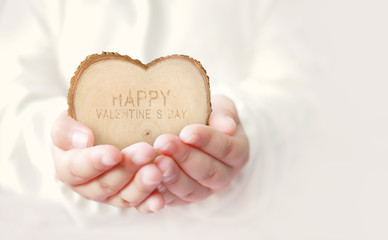 Asian young girl with wood heart in hands.Valentine's day concept background with wording " HAPPY VALENTINE'S DAY".
