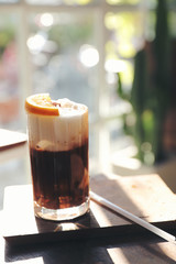 Ice black coffee with orange on wood background