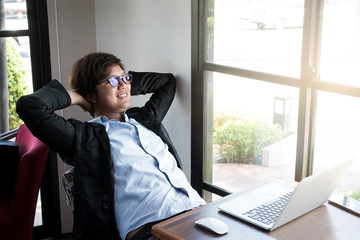 Young businessman relaxing at his desk in coffee shop