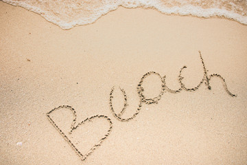 Beach word is written on the beach sand