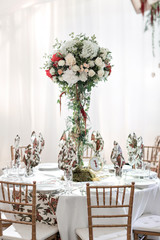 Interior of a wedding tent decoration ready for guests. Served round banquet table outdoor in marquee decorated flowers and silk. Catering concept