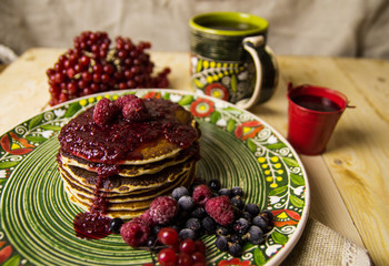 A pancake on the Christmas table with tea and raspberry jam