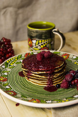 A pancake on the Christmas table with tea and raspberry jam