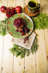 A pancake on the Christmas table with tea and raspberry jam