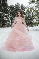 Fototapeta premium Girl in a beautiful pink dress in a winter forest