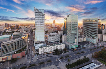 Obraz premium Warszawskie miasto z nowoczesnym wieżowcem o zachodzie słońca, Polska