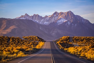 A road in Eastern Sierra leading up to a beautiful snow coverred mountain with morning light - 187429948