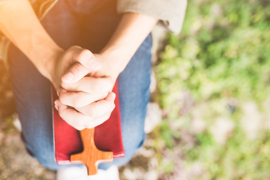 man praying on holy bible in the morning.teenager man hand with Bible praying,Hands folded in prayer on a Holy Bible in the garden concept for faith, spirituality and religion
