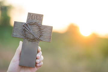 Woman hands holding a holy cross, crown of thorns and nail.