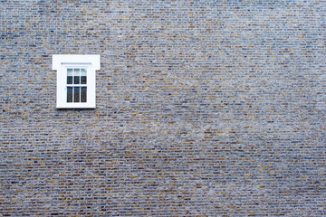 Small white window on a big brick empty wall