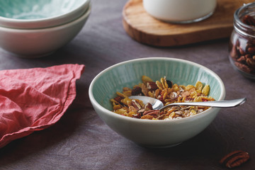 Muesli with dried berries and pecan nuts in ceramic bowl. Close-up of breakfast table.