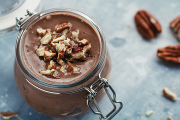 Close-up of chocolate mousse in the glass jar with pecan nuts.