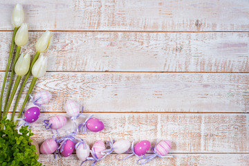 Colorful easter eggs and tulips over white wooden table