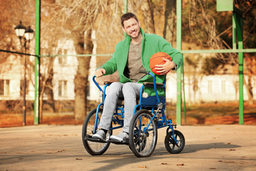 Obraz premium Young man in wheelchair with ball on playground